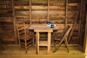 A rustic wooden table with two chairs, a small table, and two blue mugs on the table.