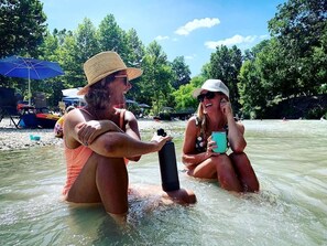 Two people in a body of water, one holding a black object and the other holding a blue object.