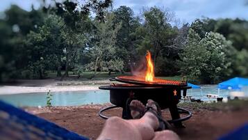 A person relaxing by a campfire with a view of a lake and trees.