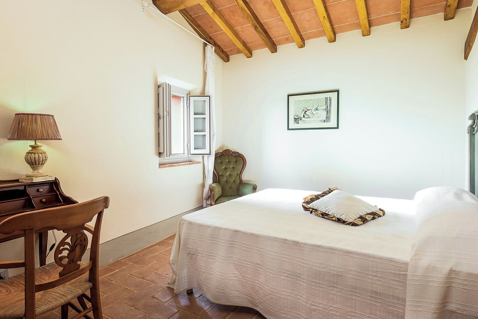A bedroom with a bed, a chair, a desk, a lamp, and a window.