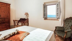 Ein Schlafzimmer mit Bett, einem Holztisch, einem Stuhl, einem Fenster mit Blick und einem großen Schrank aus Holz.