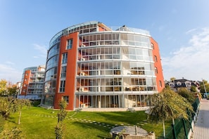 A modern multi-story building with large glass windows and a curved facade. - LSC Apartmenthotel (Siófok)