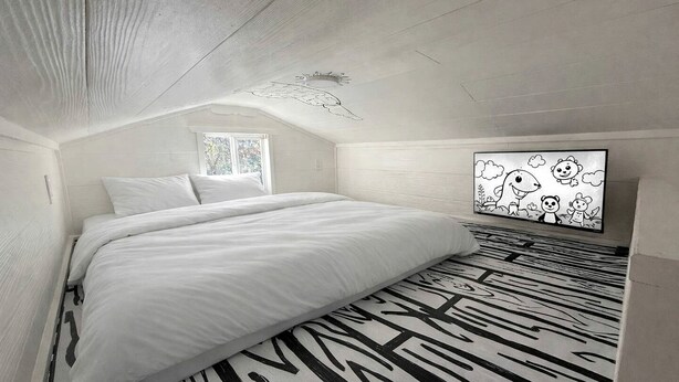 A bedroom with a bed, a window, a wall-mounted artwork, and a patterned floor.