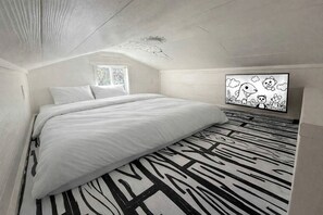 Quarto com cama, janela, obra de arte na parede e piso estampado.