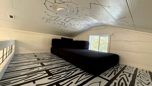 A room with a black sofa, patterned carpet, and a ceiling with star-like designs.