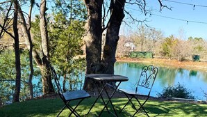 A picnic table and chairs by a lake with trees in the background.
