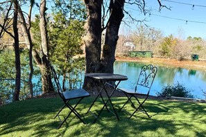 Uma mesa e cadeiras de piquenique perto de um lago, com árvores ao fundo.