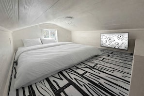 A bedroom with a bed, a window, a wall-mounted artwork, and a patterned floor. - Whimsical Lakefront Tiny Home with Hand-Drawn Doodle Design Near Bastrop, Texas (Bastrop)