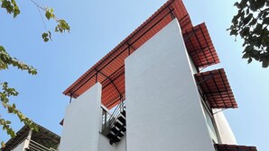 A two-story building with a red-tiled roof, a staircase, and a motorbike parked in front.