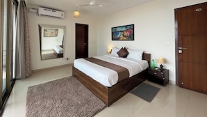 A bedroom with a bed, a ceiling fan, a wall-mounted air conditioner, a painting, and a door.