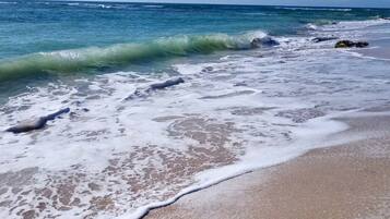 A beach with waves, clear sky, and distant horizon.