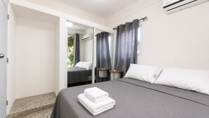Un dormitorio con cama, espejo, armario y aire acondicionado.