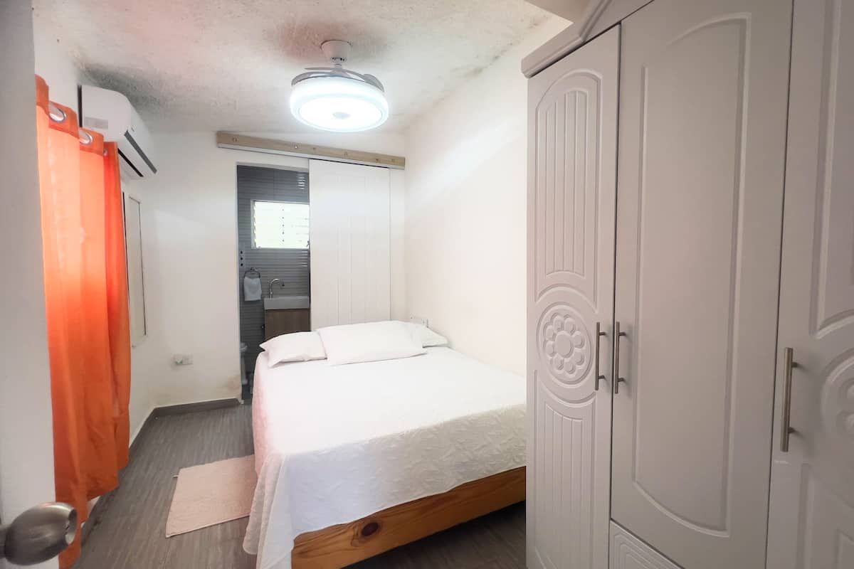 A bedroom with a bed, a wardrobe, a ceiling fan, and a window.