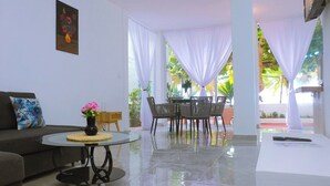 Una sala de estar con un sofá, una mesa de centro, un comedor con sillas y vistas al exterior.