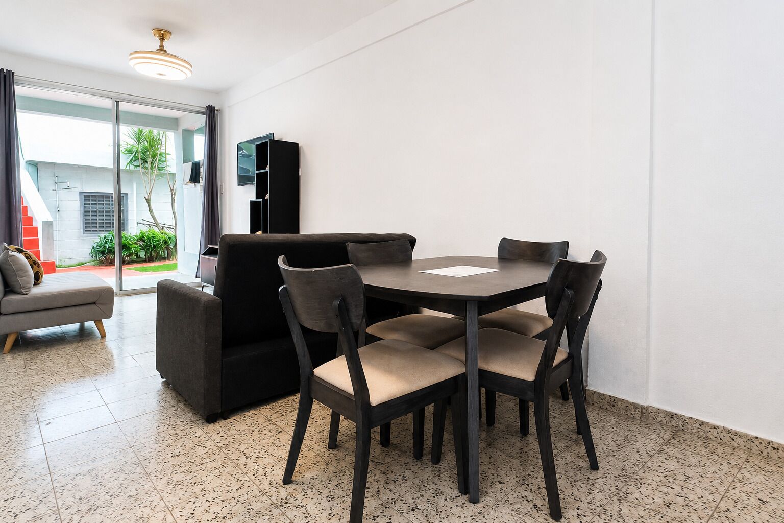 A modern living room with a dining table, chairs, a sofa, and a TV.