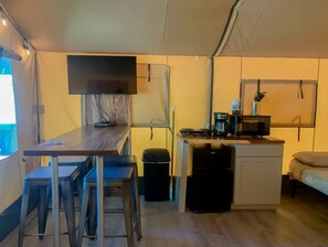 A compact kitchen with a dining area, a small refrigerator, and a microwave.