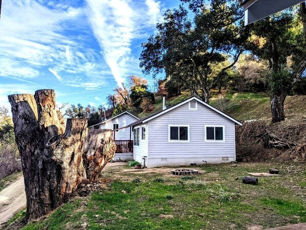 A single-story house with a front porch, a small yard, and a dirt path leading to the house.