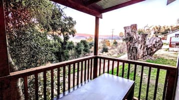 Une terrasse en bois avec une table et des chaises, entourée d’arbres et offrant une vue sur un paysage.