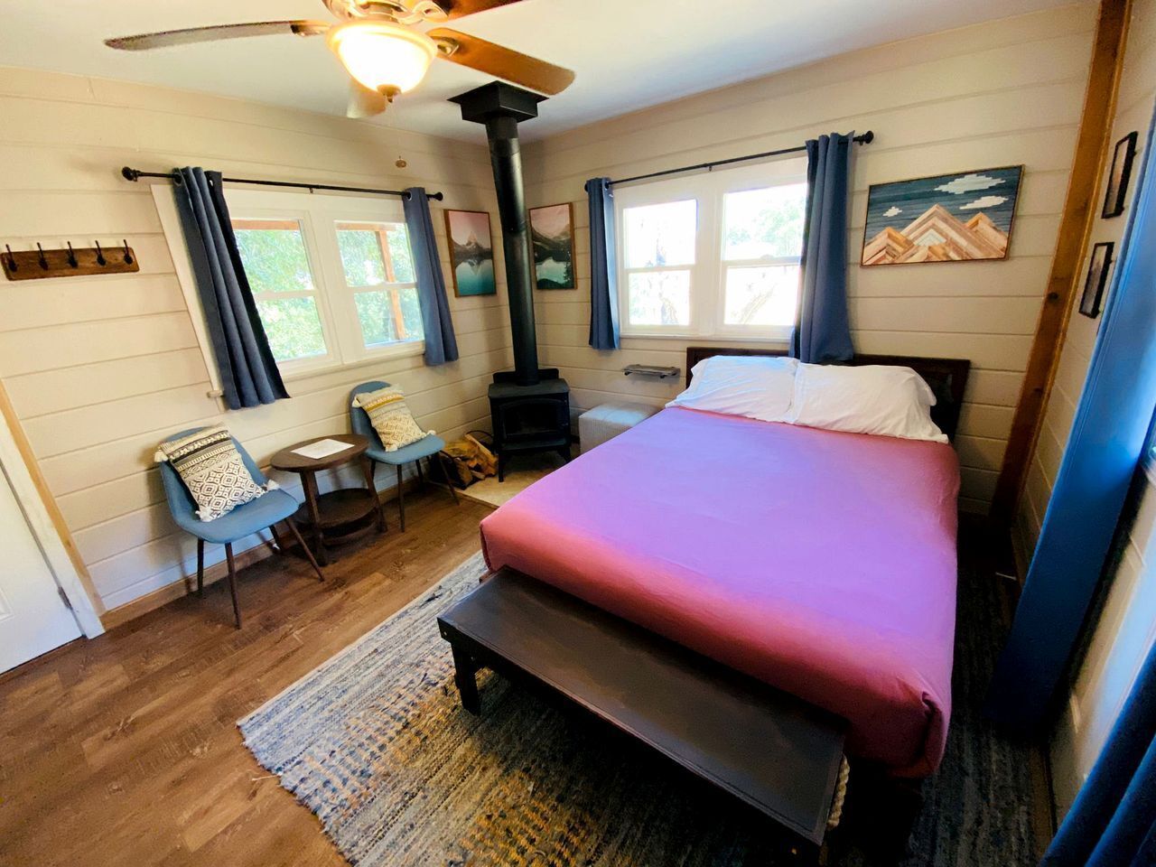 A bedroom with a bed, a heater, a chair, a table, and a window.