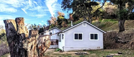 A single-story house with a front porch, a small yard, and a dirt path leading to the house.