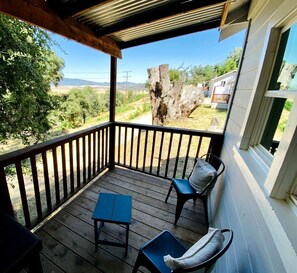 Varanda coberta com mesa e cadeiras, com vista para uma paisagem rural.