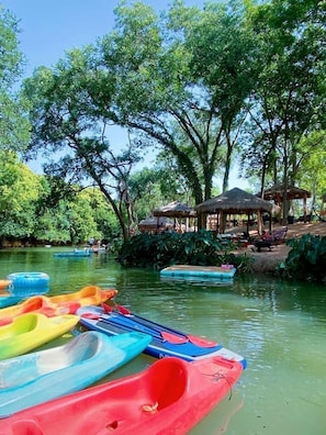 A calm water body with kayaks and a gazebo in a lush, green setting.