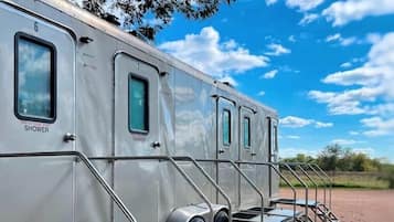 Una hilera de vehículos recreativos con duchas exteriores y escalones que conducen a la entrada.