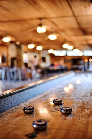 A blurred indoor setting with a wooden ceiling and a reflective surface with objects on it.