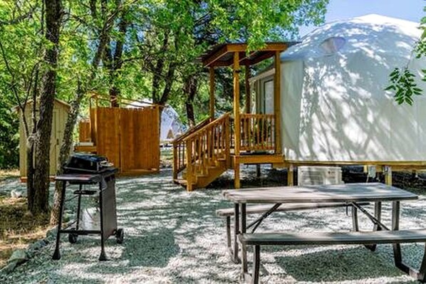 Un espacio al aire libre techado con una terraza de madera, una parrilla y una mesa de picnic.