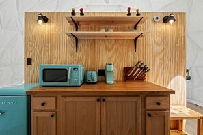 Eine Küche mit einer Holzausstattung, einer türkisfarbenen Mikrowelle, einer Kaffeemaschine und einem Messerblock.