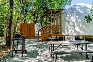 A covered outdoor area with a wooden deck, a grill, and a picnic table.