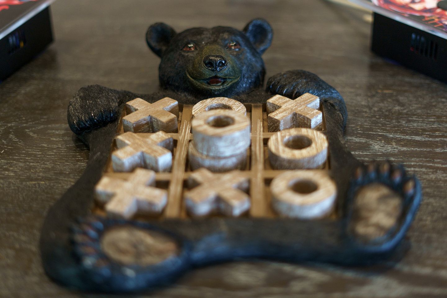Un jeu de société en bois en forme d’ours, avec une grille composée de symboles « X » et « O ».