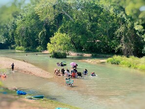 A river with people engaging in various activities, surrounded by lush greenery.