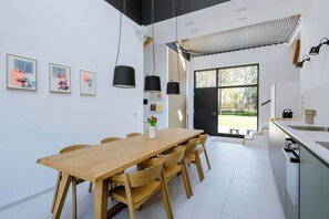A modern kitchen with a wooden dining table, chairs, and a large window.