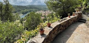 Un muro de piedra con plantas en macetas, con vistas a un río y un pueblo.