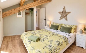 Un dormitorio con cama, vigas de madera, un adorno de estrella y una mesita de noche con lámpara.
