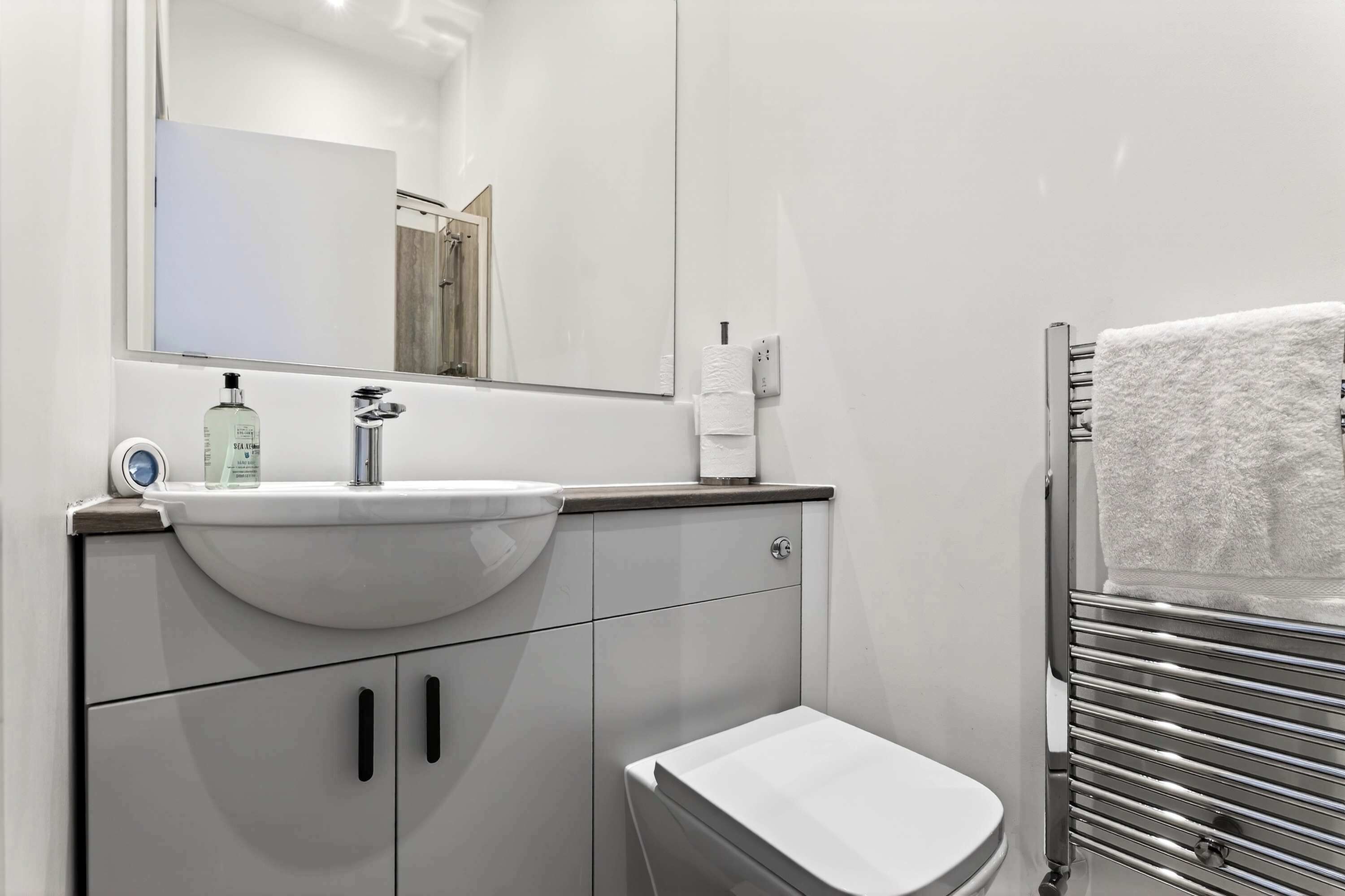 A modern bathroom with a sink, toilet, and towel rack.
