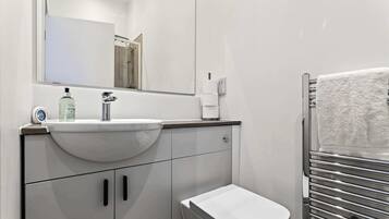 A modern bathroom with a sink, toilet, and towel rack.