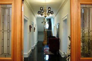 A hallway with a chandelier, a staircase, and a red chair.