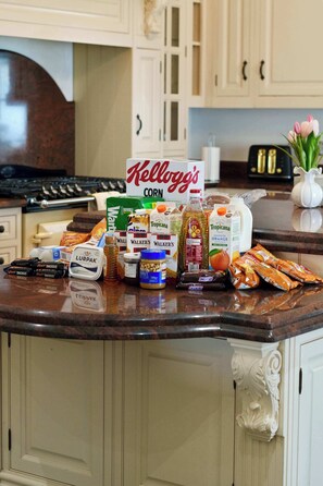 A kitchen counter with various food items and a sign for Kellogg's Corn Flakes.