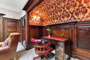 A room with a red leather chair, a desk with drawers, a lamp, and a patterned wallpaper. - Charming 4-bed in a Scottish Baronial mansion (Renfrewshire)
