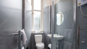 Moderni kylpyhuone, jossa on wc, pesuallas ja lasinen suihkuseinä.