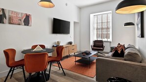 A modern living room with a dining area, a sofa, a TV, and pendant lights. - Modern City Apartment Just off Buchanan St (Glasgow City)