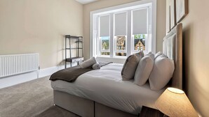 Ein Schlafzimmer mit Bett, Fenster, Heizkörper und Lampe.