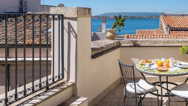 Une terrasse avec une table dressée pour le petit-déjeuner, offrant une vue sur la côte.