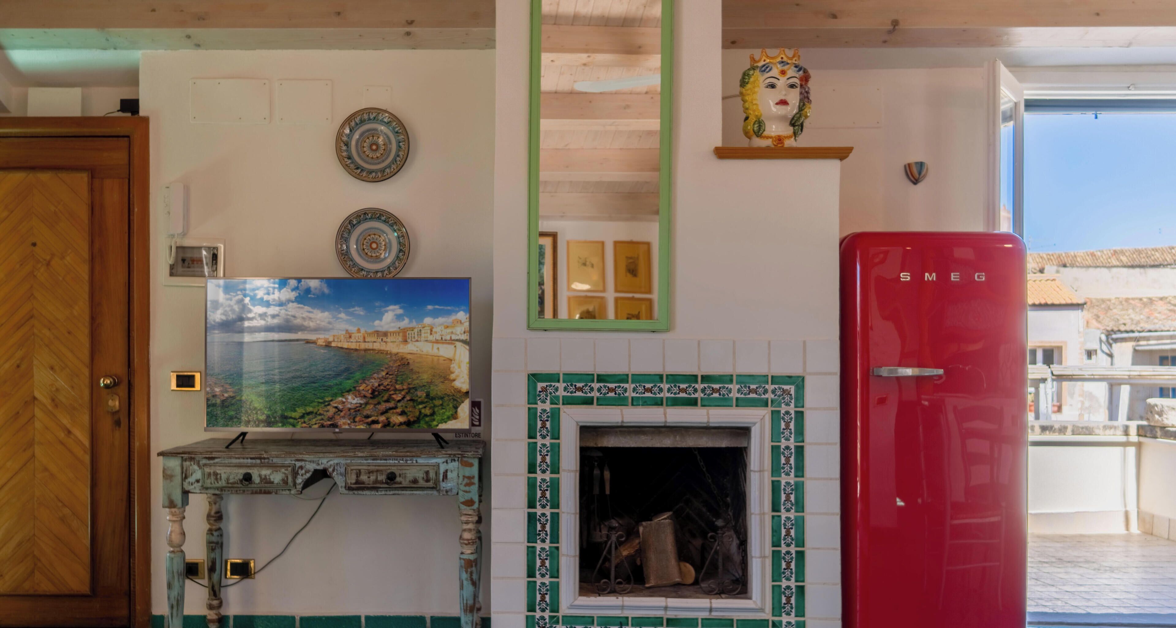 Una cocina con un refrigerador rojo, un espejo decorativo y un salpicadero de azulejos.