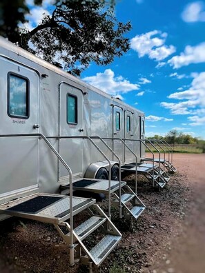A row of RVs with external shower facilities and steps leading to the entrance.