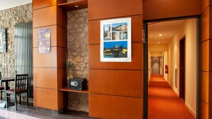 A hotel lobby with a stone wall, a reception desk, a poster, and a corridor leading to rooms. - 6-guest Stay With Wellness Area (Dinan)