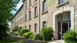 A stone building with a restaurant sign, a paved entrance, and surrounding greenery. - 6-guest Stay With Wellness Area (Dinan)