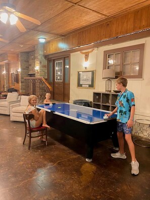 A room with a ping pong table, a wooden ceiling, and a stone wall.